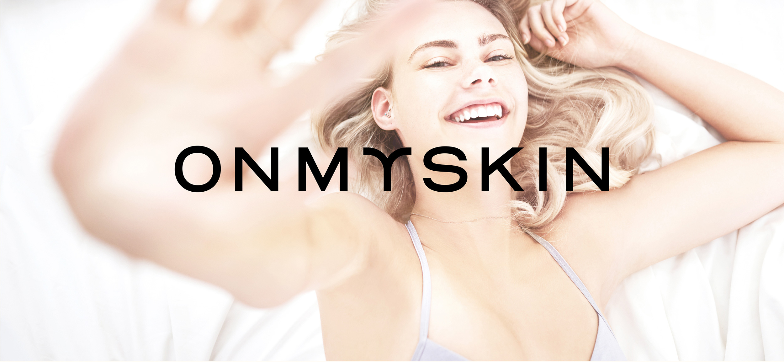 Onmyskin Logo im Hintergrund eine lachende Frau in Unterwäsche